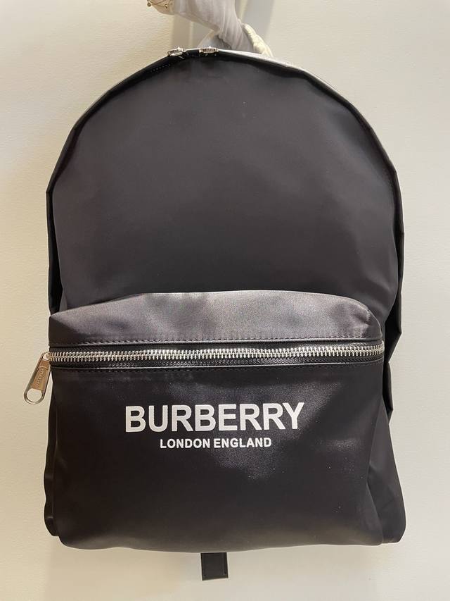 Burberry新款尼龙双肩包 印有焕新的品牌标识logo 搭配平滑皮革边饰 肩带饰有burberry字母提花精仿微标 底部使用牛皮材质 双向拉链开合 亮泽金属