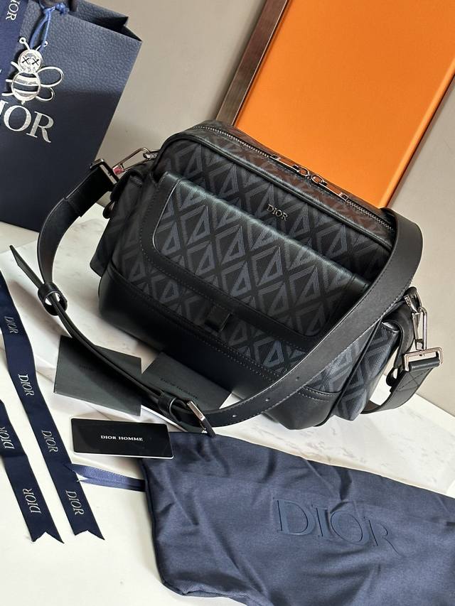 配盒子 这款 Dior Hit The Road 信使包是本季新品，将现代风格与 Dior 的高订精神融为一体。采用迪奥灰 Cd Diamond 图案帆布和光滑