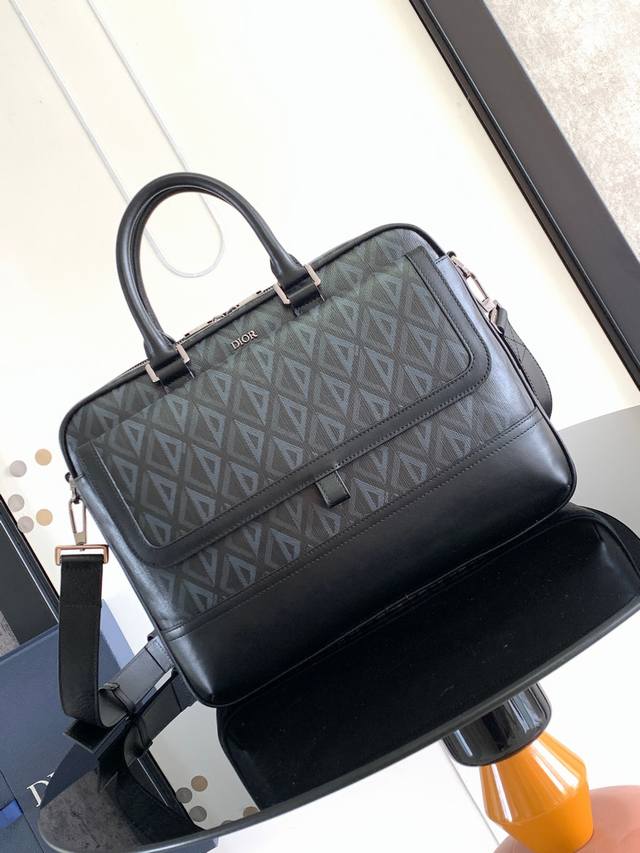 这款 Dior Hit The Road 公文包是二零二三夏季新品，将现代风格与 Dior 的高订精神融为一体。采用黑色 Cd Diamond 图案帆布和光滑牛