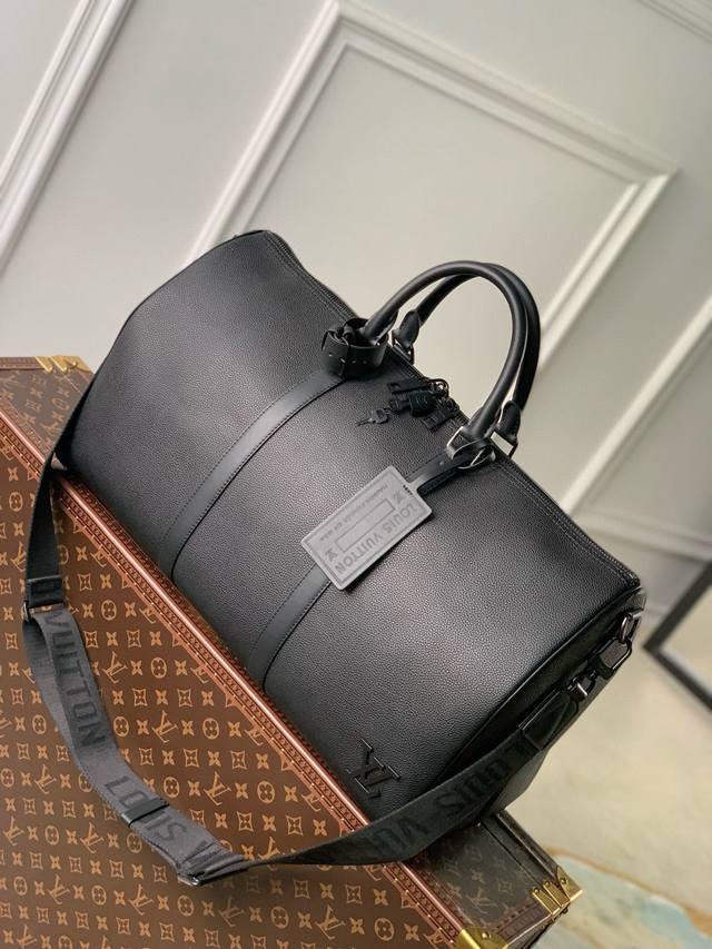 路易威登 M21420黑色本款 Keepall 旅行袋选用 Lv Aerogram 牛皮革塑造经典构型，见证路易威登的精湛皮革匠艺。皮革标签和提花肩带援引品牌旅