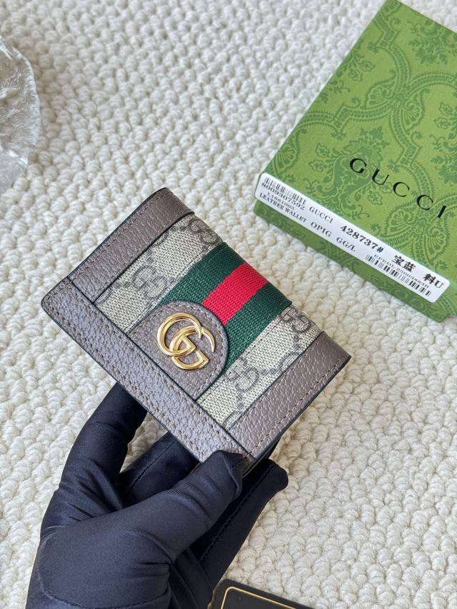 Gucci 折叠卡片夹，配以醒目的标志性双 G 金属配件。采用帆布配织带制作，以营造织纹外观。 型号：428737 尺寸：10.5×7.5×2.5