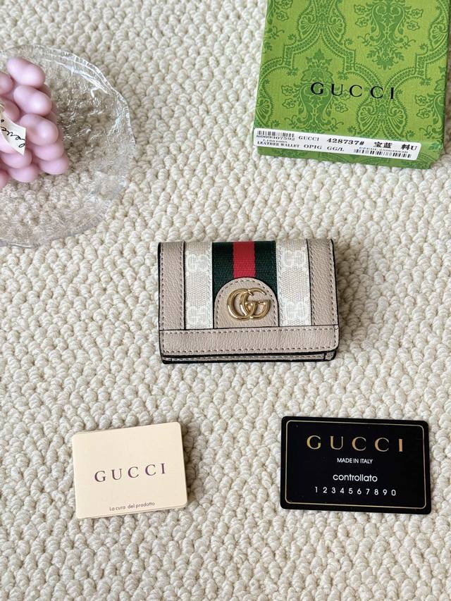 Gucci 折叠卡片夹，配以醒目的标志性双 G 金属配件。采用帆布配织带制作，以营造织纹外观。 型号：428737 尺寸：10.5×7.5×2.5