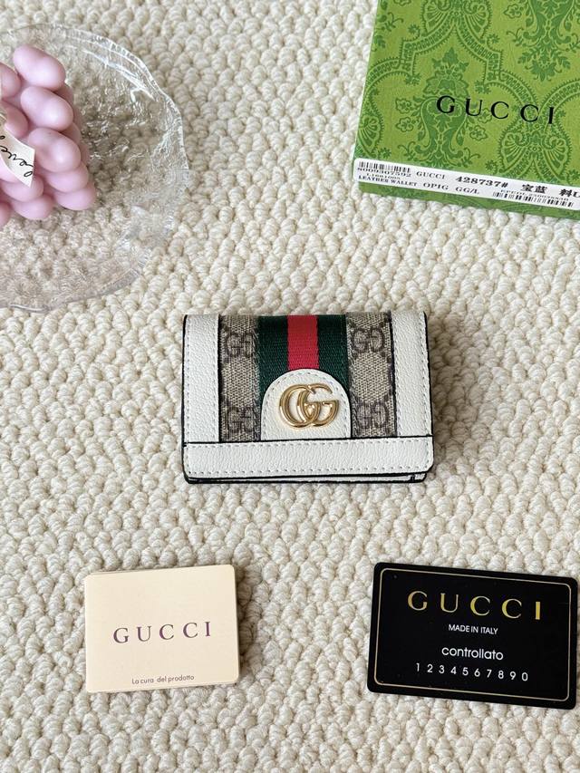 Gucci 折叠卡片夹，配以醒目的标志性双 G 金属配件。采用帆布配织带制作，以营造织纹外观。 型号：428737 尺寸：10.5×7.5×2.5